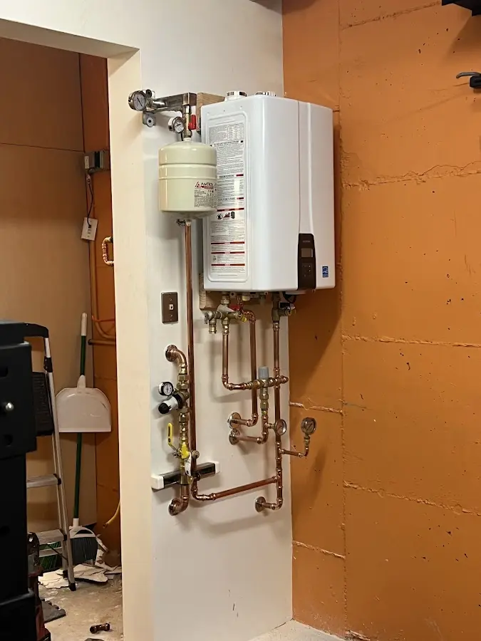 Plumbing technician inspecting water heater connections in Penn